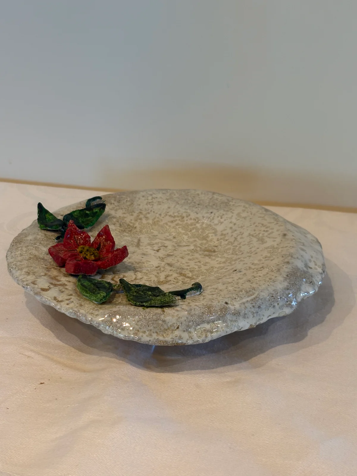 Fat med blomst og grønt festet på sølvfarget bakgrunn.